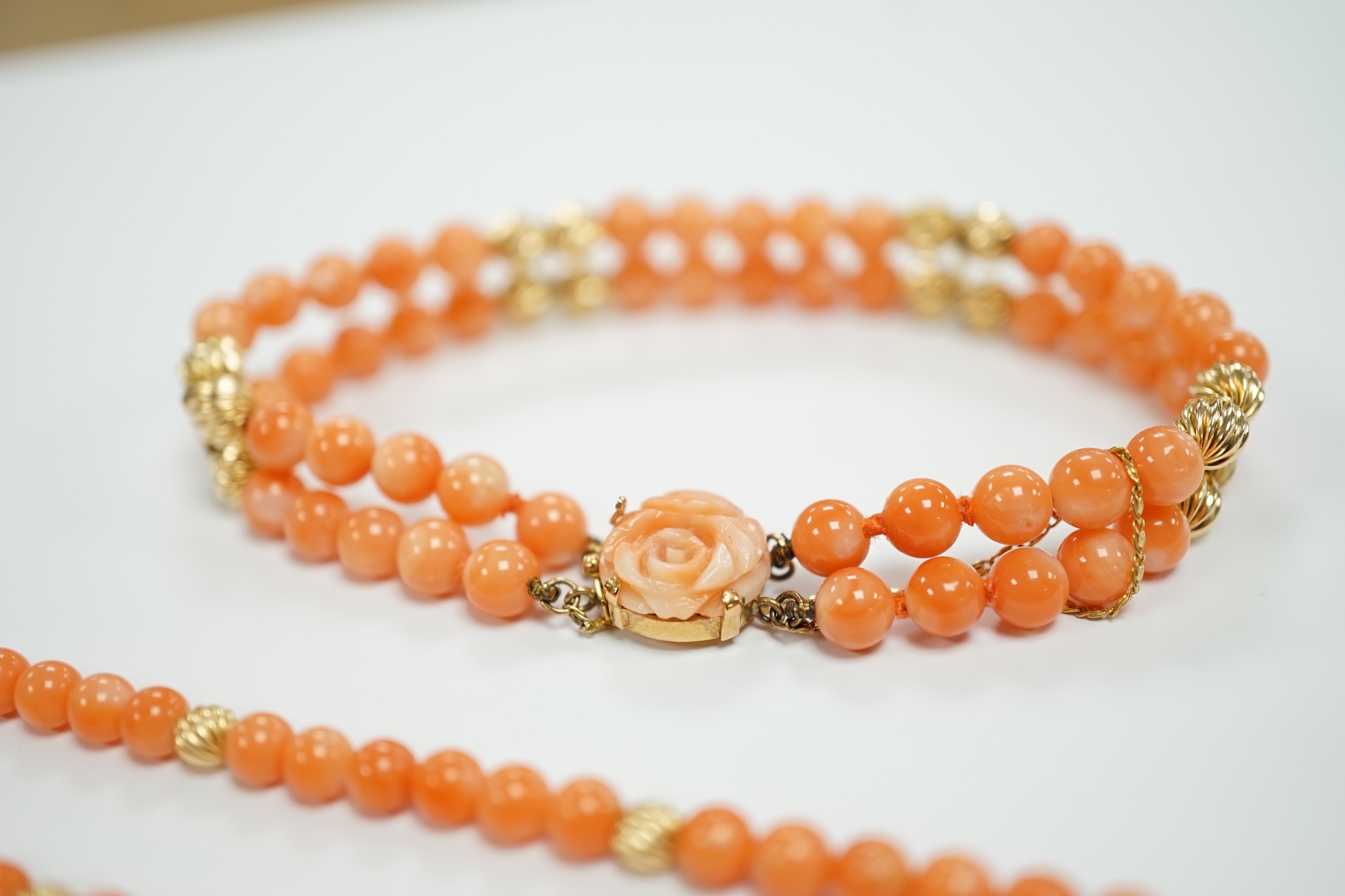 A modern 14k mounted twin strand coral bead necklace, 17cm, together with a 14k mounted single strand coral bead necklace, 44cm.